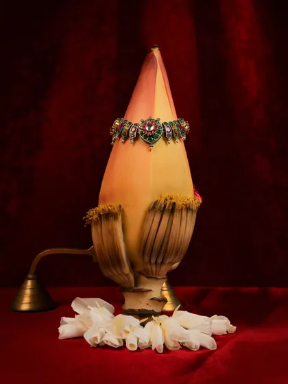 A still-life product shot of a beautiful piece of jewelry, creatively displayed on a banana flower. This unique, organic presentation is artistic and makes the product stand out.