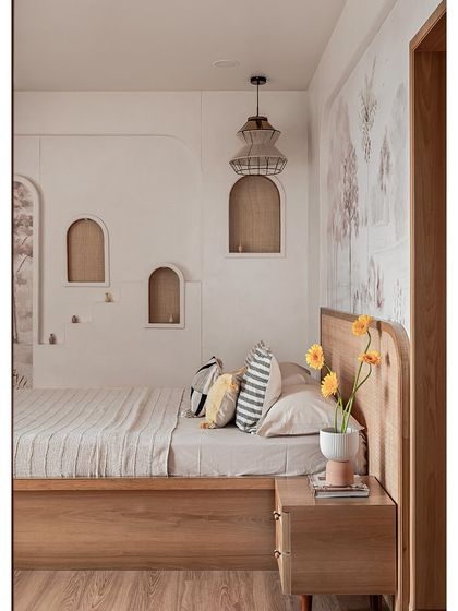 A fuller view of the master bedroom's feature wall with its micro-topped finish and arched niches. The custom bed with a cane headboard and the soft pastel wallpaper complete the serene look.