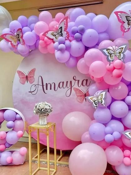 A lovely butterfly theme for a 2nd birthday. The pink and purple balloon arch is decorated with silver butterfly cutouts, and a balloon-filled number '2' adds a special touch.