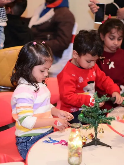 Little ones engaged in a Christmas craft activity, decorating mini trees.