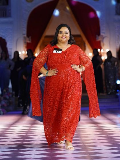 A plus-size model in a bright red gown with flowing sleeves. This is a power look, full of confidence and glamour.