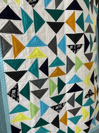 A close-up of the Twisted Geese blocks, showing the crisp, straight-line quilting.
