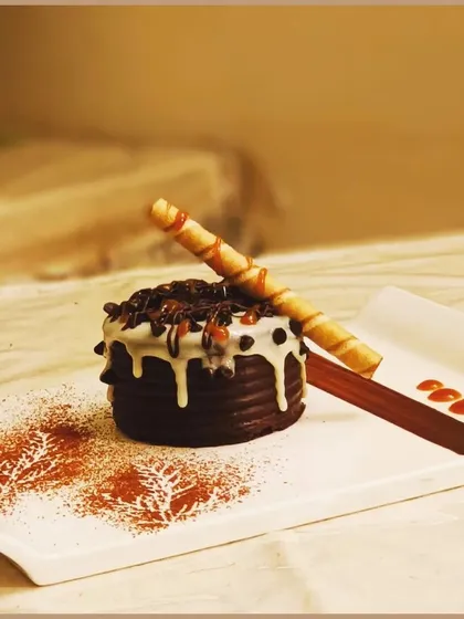 A closer look at one of our decadent chocolate desserts. It's carefully plated with artistic cocoa powder stencils and a crunchy wafer roll for the perfect finish.