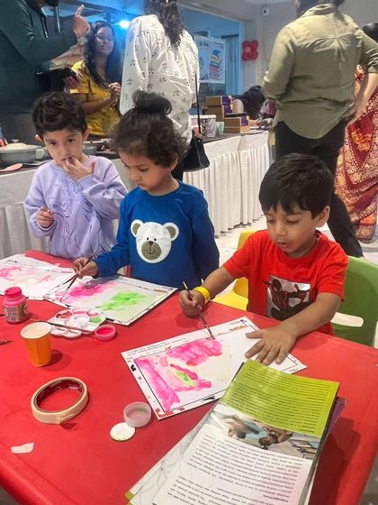 Three young boys are completely focused on their watercolor painting during a creative session at the Lit Fest.