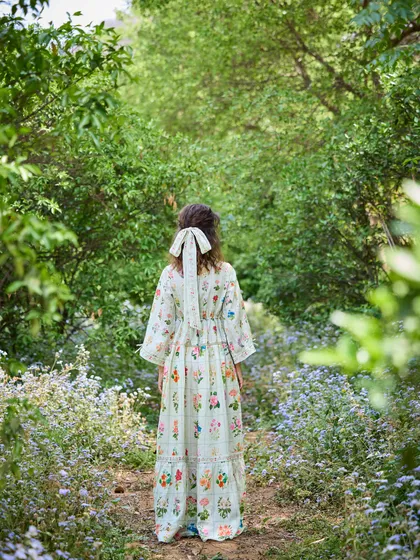 A back view of the same dress, highlighting the bow detail in the hair and the way the model blends into the natural surroundings. This shot is all about creating a mood and a story.