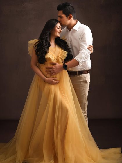 A beautiful portrait of the couple, with the dad-to-be's gentle touch conveying love and support. The golden-yellow gown adds a vibrant and joyful feel to the image.