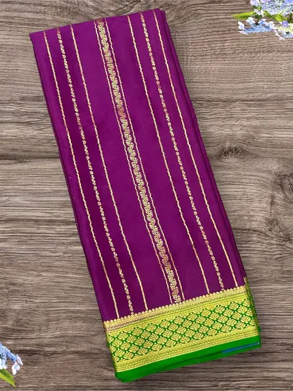A rich purple pure crepe Mysore silk saree featuring vertical gold stripes and a vibrant green contrast border.
