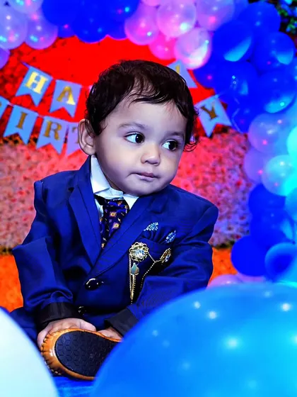 A close-up shot of a young boy in his birthday suit, surrounded by blue balloons, creating a vibrant and festive portrait.