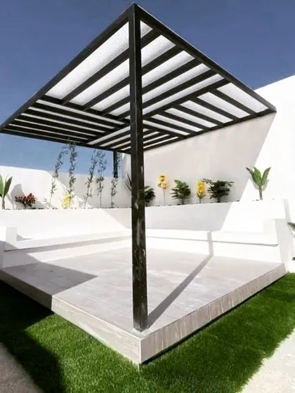A minimalist pergola with a black metal frame and a white louvered roof. The structure is built on a raised concrete platform with integrated stepped seating, perfect for a modern, clean aesthetic.