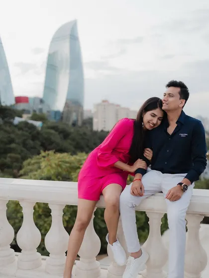 A colorful and happy pre-wedding photo from Baku. Her bright pink dress stands out against the city skyline, and her joyful expression is infectious. This shot is full of life and love.