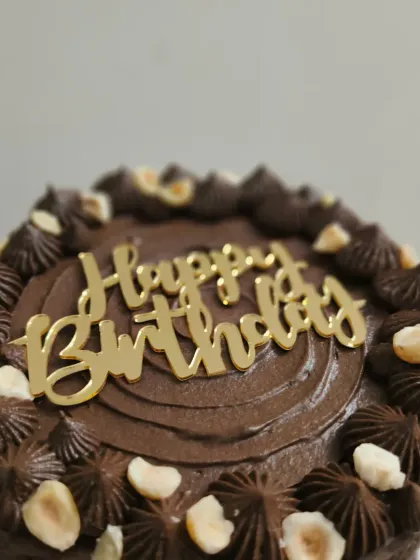 A close-up of the chocolate hazelnut cake, showing the piped border and generous topping of nuts.