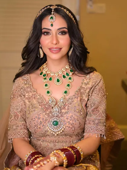 A portrait of our bride, exuding the grace and grandeur of a bygone era. The makeup is flawless, with a focus on warm tones and a radiant finish.