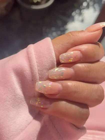 Sheer gel extensions with iridescent, confetti-like glitter embedded within the nail for a subtle, multi-colored sparkle.