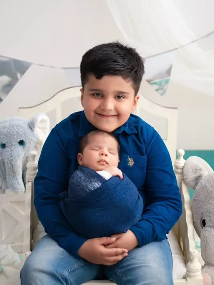 A big brother's proud embrace. We created a dreamy, cloud-like setting with soft blue tones and plush elephants to capture this sweet moment between two brothers.