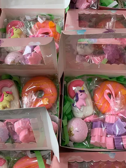 A box filled with unicorn magic, including a popsicle soap, mini unicorn soaps, a fizzy bath bomb, and a pink donut soap.