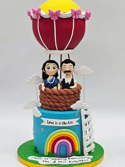 A whimsical hot air balloon cake for a 31st wedding anniversary, featuring custom figurines of the couple.
