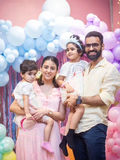 Just perfect. A beautiful family portrait in front of a pastel rainbow balloon backdrop.