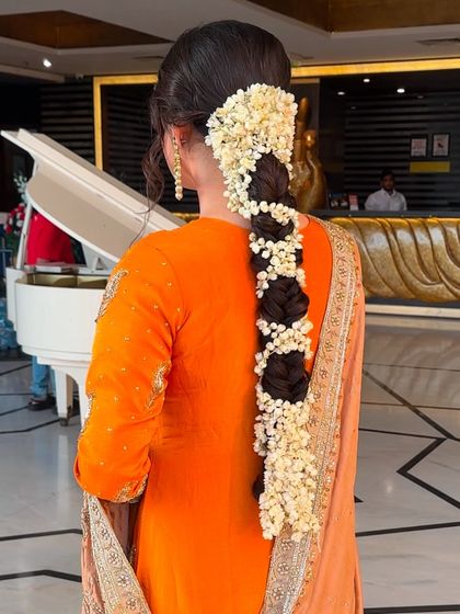A still image of the full jasmine-wrapped braid, showing its impressive length and the beauty of the fresh flowers against the bride's orange suit.