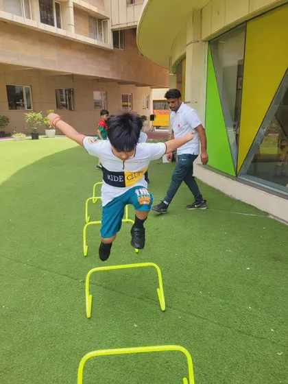 A young boy energetically jumps over hurdles, showcasing the dynamic and active start to our Summer Camp. We focus on making fitness fun and engaging for all our students.