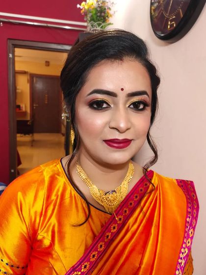 A portrait of the client, looking elegant and ready for her event in a bright orange and pink saree.