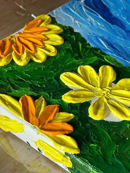 A detailed shot of the thick, textured petals of a sunflower created with a palette knife, showcasing the impasto technique taught in our workshops.