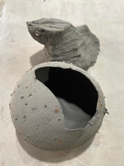 An abstract, broken sphere sculpture. This piece explores deconstruction and imperfection, showing beauty in a form that is not perfectly whole.