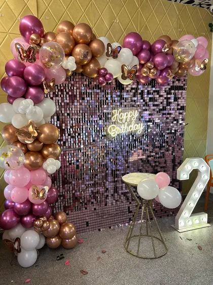 The butterfly accents on this rose gold balloon arch add a whimsical touch to the glamorous 2nd birthday setup.