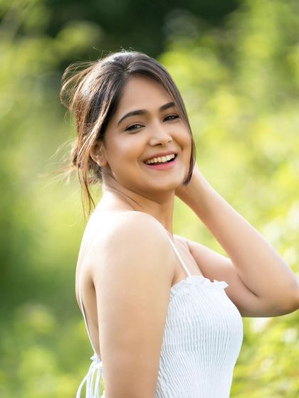 A natural, effortless portrait taken outdoors. The focus is on the model's genuine smile and the soft, flattering light.