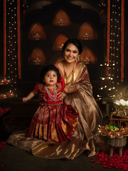 A beautiful mother and daughter portrait for Diwali. The little one looks like a princess in her traditional red dress, surrounded by the soft glow of diyas.