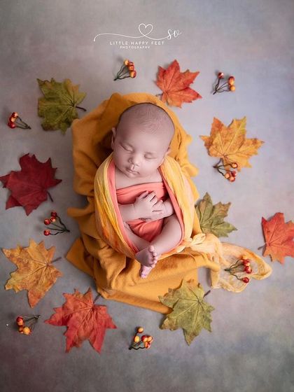 Our little autumn miracle. This simple, artistic shot with a baby wrapped in yellow and surrounded by fall leaves is both modern and timeless.
