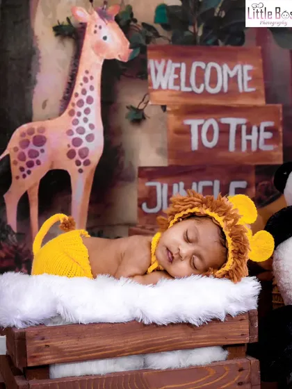 Welcome to the jungle! This little one is dressed as a tiny lion, sleeping peacefully in a setup complete with a giraffe, panda, and jungle signs.