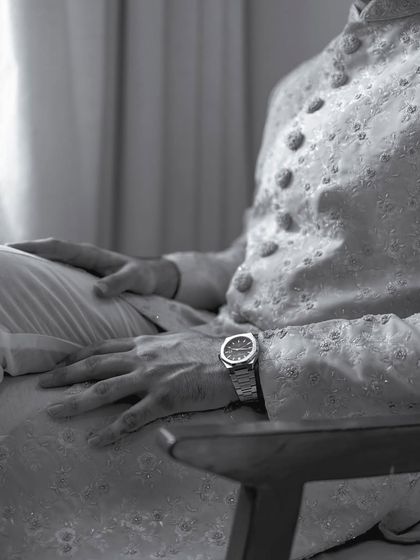 A close-up black and white shot of the groom's attire and watch. The focus on texture and detail adds a sophisticated touch to his portrait series.