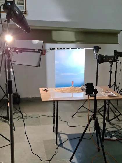 Our studio setup for a beach-themed liquid blush shoot. We used a large monitor for the sky background, real sand, and multiple lights to create a sunny, outdoor feel indoors.