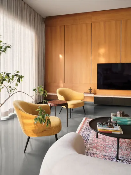 A sunlit living room corner with vibrant yellow armchairs providing a pop of color against a neutral backdrop of wood and sheer curtains.