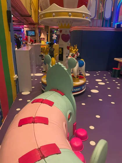 A view of our colorful and whimsical play area, with the carousel in the background. We've designed the space to be visually stimulating and magical for children.