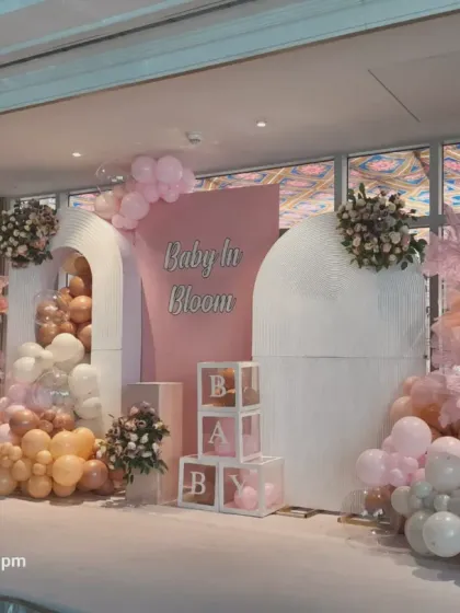 Another angle of the "Baby in Bloom" setup, showing the full scale of the stage design. The combination of balloon cascades, floral pieces, and 'BABY' blocks creates a stunning focal point.