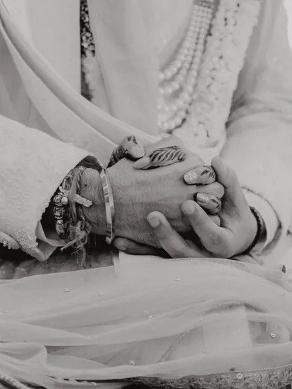 A black and white close-up of the couple's hands clasped together during the ceremony, a symbol of their union.