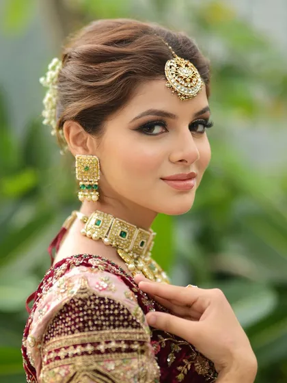 A classic bridal portrait. I created a soft glam look with defined eyes and a neutral lip color to complement her ornate jewelry and pastel lehenga. The hair is styled in an elegant bun adorned with fresh flowers.