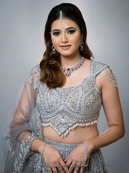 This silver lehenga is brought to life with a pop of color from our ruby and zircon necklace set. The matching maang tikka and hath phool complete this glamorous look, perfect for a reception.