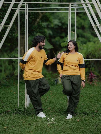 The couple posing playfully against a white structure, their candid interaction making for a great shot.