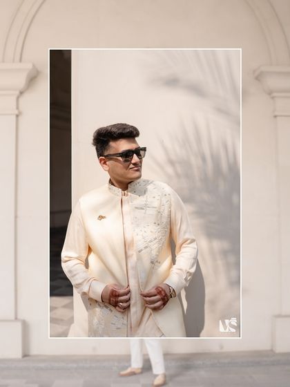 A stylish groom portrait. Hrithik's modern, embroidered jacket and cool sunglasses create a look that is both traditional and contemporary. The play of light and shadow adds a dynamic feel.