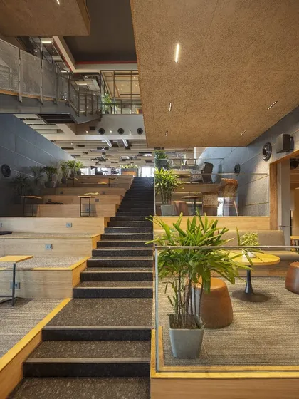 A view from the base of the atrium at Primarc shows how the terraced design creates inviting pockets for pause and conversation. This unconventional layout balances focused work with social interaction, ensuring the space feels deeply human.