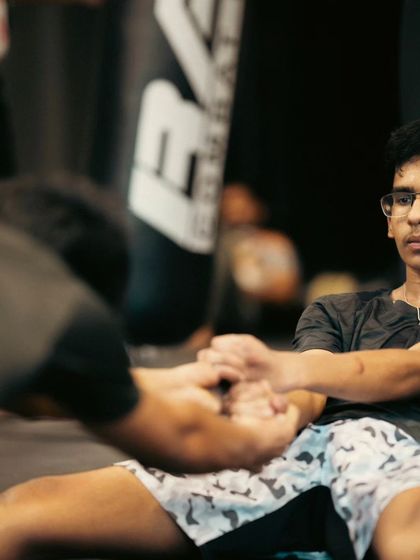 Flexibility is key to preventing injuries and executing techniques like high kicks. Here, a student works on a seated stretch with assistance to improve his range of motion.