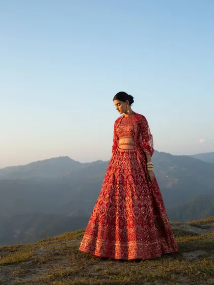 A high-fashion bridal shoot for Frontier Raas, set against the stunning backdrop of the Kumaon mountains. The styling contrasts the intricate, heavy embroidery of the red lehenga with the vast, natural landscape to create a powerful and modern bridal statement.