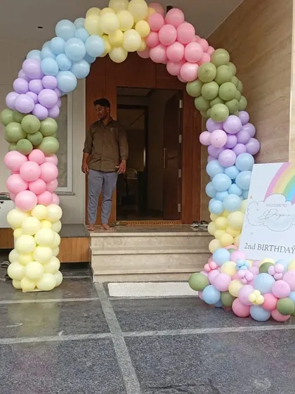 A cheerful rainbow-themed entrance arch for a second birthday party. The soft pastel colors create a welcoming and joyful atmosphere, with a matching sign to greet all the guests as they arrive.