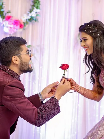 A classic romantic gesture. The groom offering a rose to his bride-to-be is a sweet, timeless moment from their engagement.