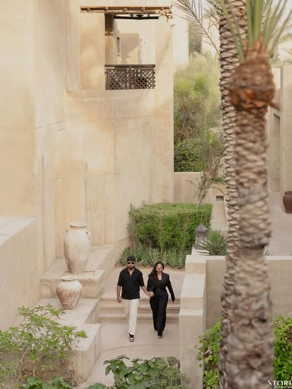 A wide shot of the couple walking through the resort, capturing the beautiful, rustic environment.