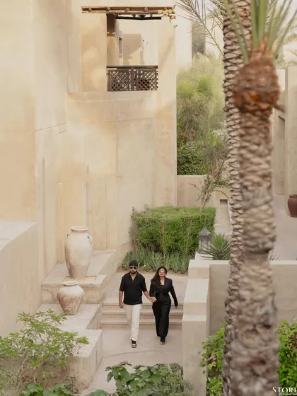A wide shot of the couple walking through the resort, capturing the beautiful, rustic environment.