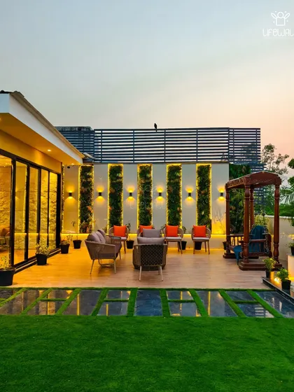 A beautiful evening shot of a completed terrace, featuring a glass house, a cozy seating area with vertical garden panels, and a traditional wooden swing.