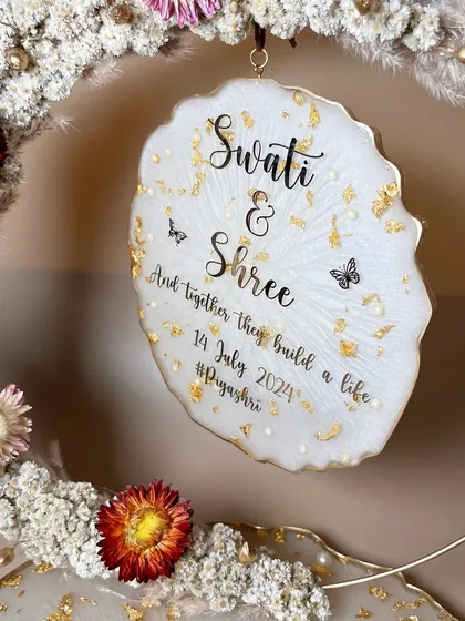 A close-up of the hanging plaque, personalized with the couple's names, date, and hashtag.